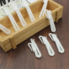 A wooden box filled with white adjustable curtain hanging hooks and various sized plastic hooks.