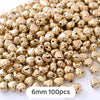 A pile of gold-colored, heart-shaped metal beads for jewelry making