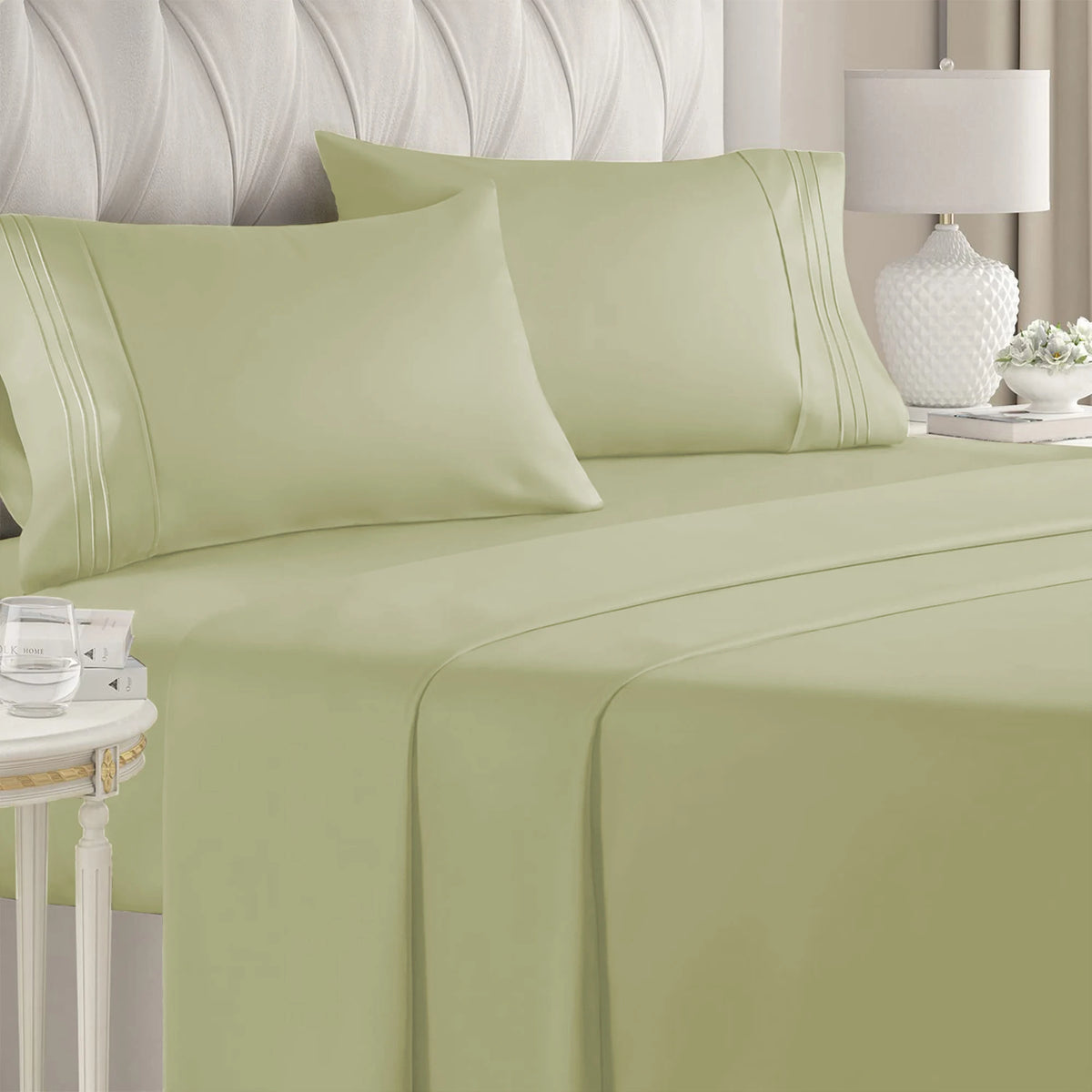 A set of light green luxury microfiber bed sheets with decorative pleats and deep pockets on a bed.