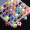 A clear plastic box filled with various colored sewing bobbins and thread spools.