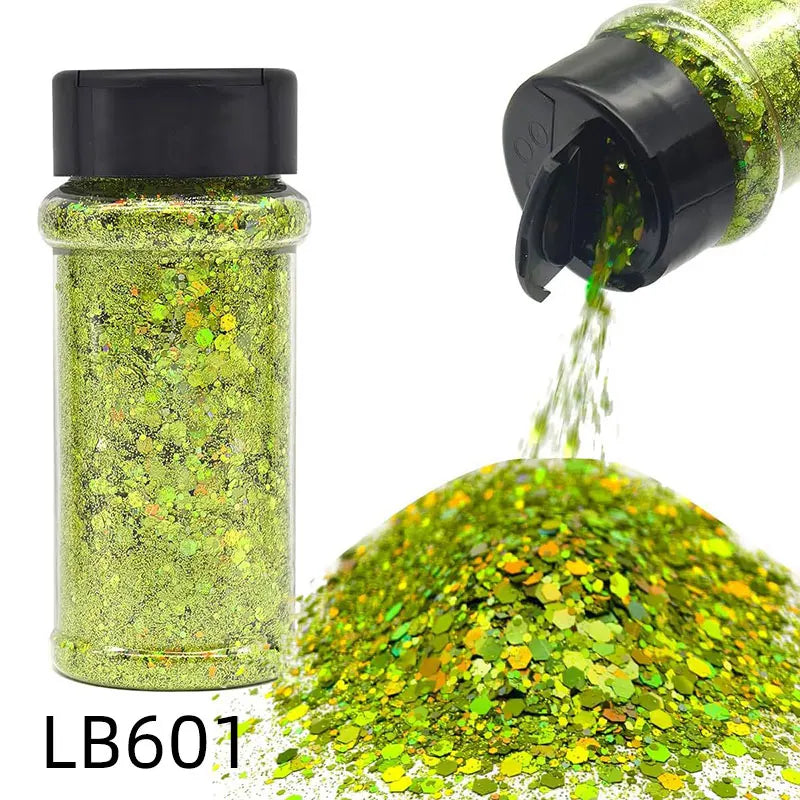 A glass jar of holographic green glitter next to a pile of loose green glitter.