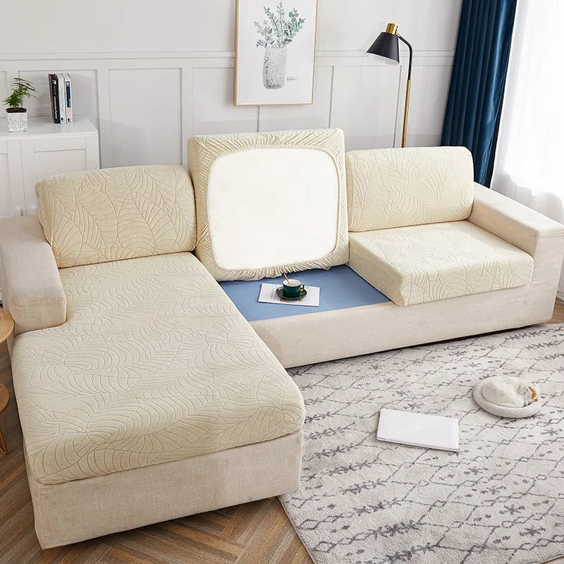 A light beige waterproof jacquard stretch sofa cover displayed on a modern sofa in a bright living room.