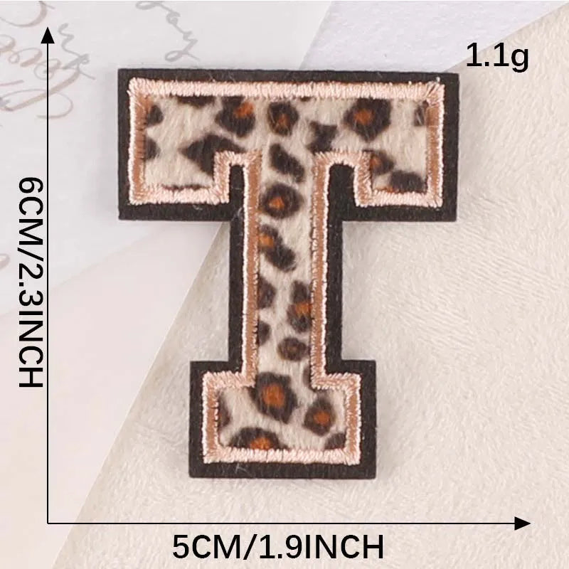 A black iron-on patch shaped like the letter T with a leopard print design.
