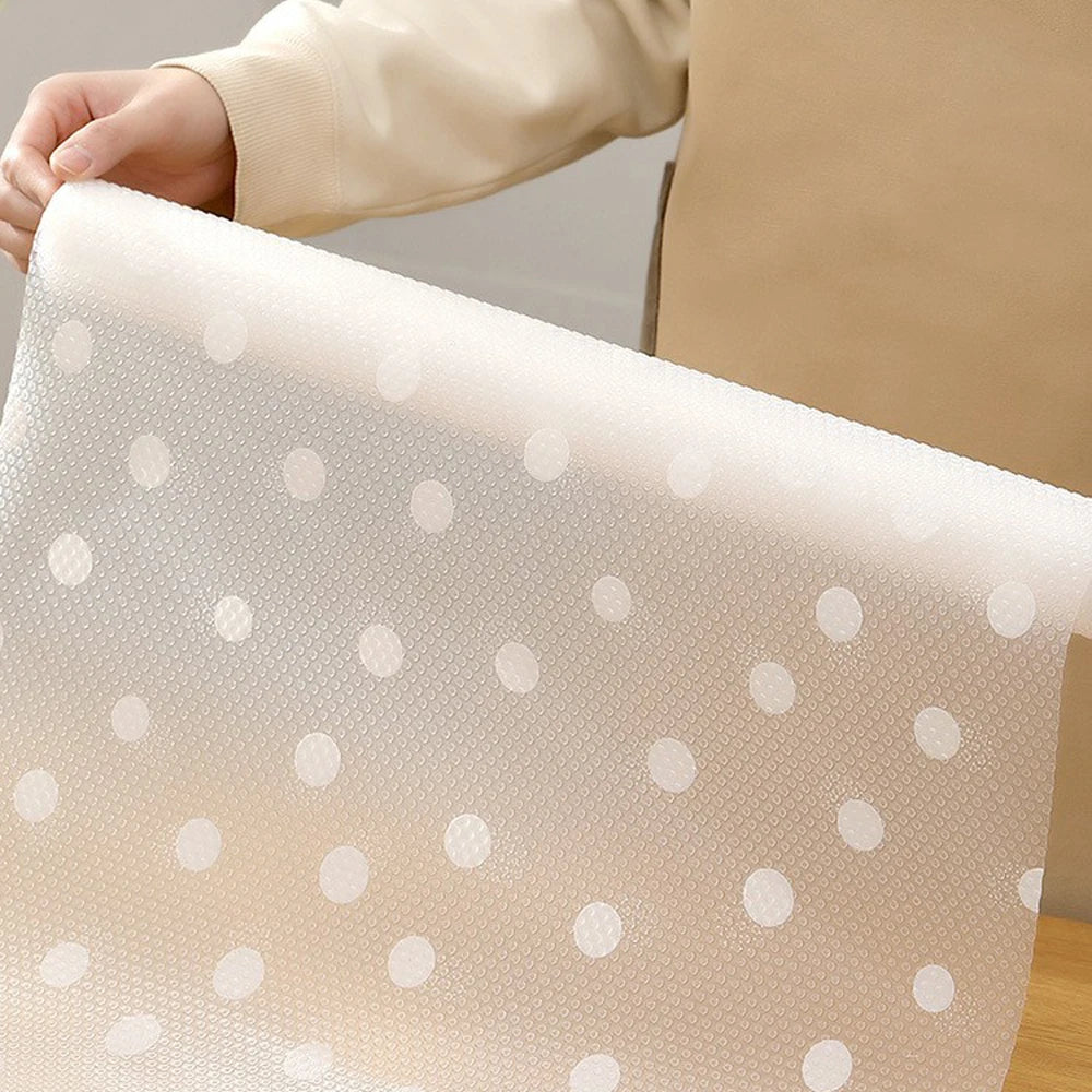 A close-up of a translucent, white silicone non-slip drawer liner with scattered white dots.