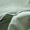 Close-up of a light green duvet cover with a silver zipper detail.