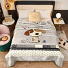 A gray blanket with a dog graphic and black and white stripes is displayed on a bed.