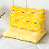 A yellow fiber pillow with a repeating pattern of cartoon ducks for infants.