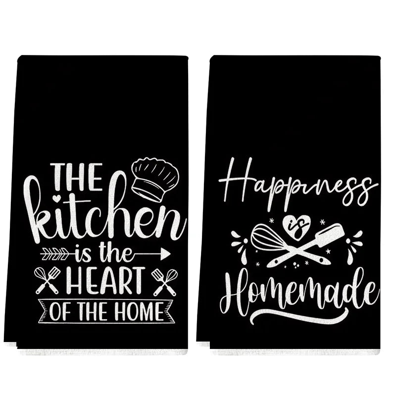A set of two black towels featuring white text about the kitchen and happiness.