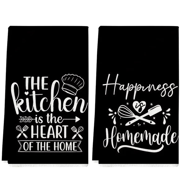 A set of two black towels featuring white text about the kitchen and happiness.