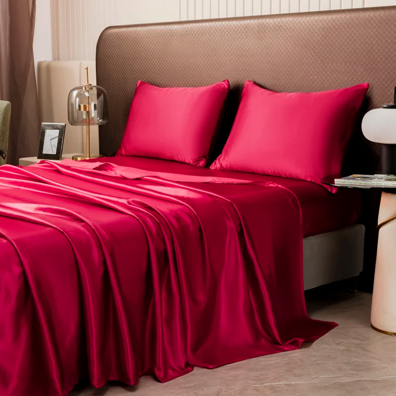 A luxurious solid satin bedding set featuring deep red sheets and pillows on a bed.
