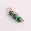 A delicate gold-toned adjustable pearl brooch featuring three round, dark green beads accented with small clear stones.