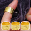 A hand is holding a gold-colored stainless steel embroidery and knitting needle ring on a finger against a dark gray knitted 