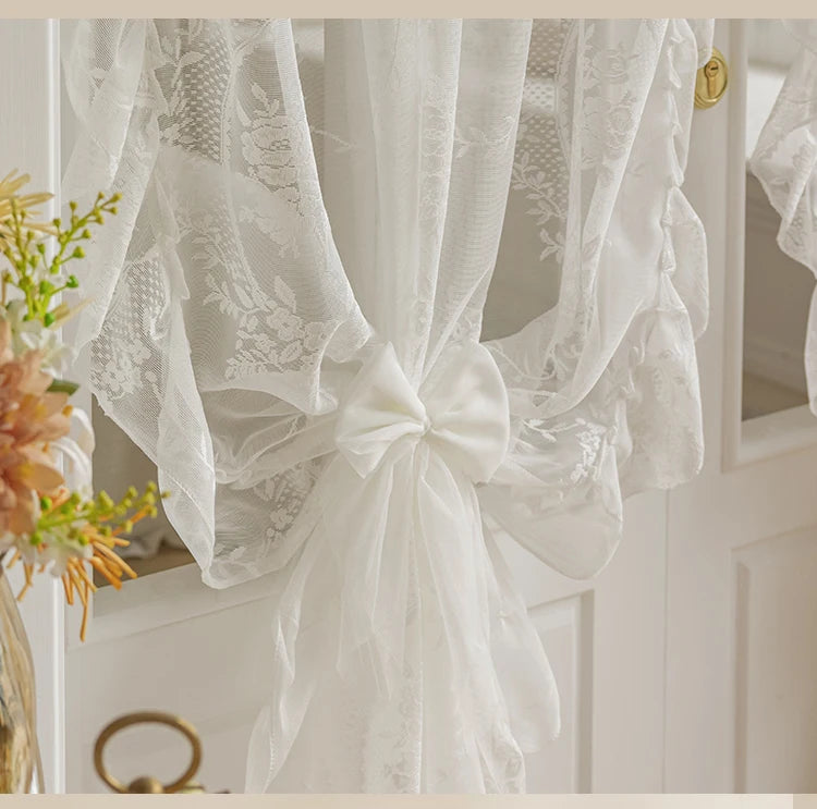 White French Rococo vintage lace curtains tied in a bow, displayed in a bright interior.