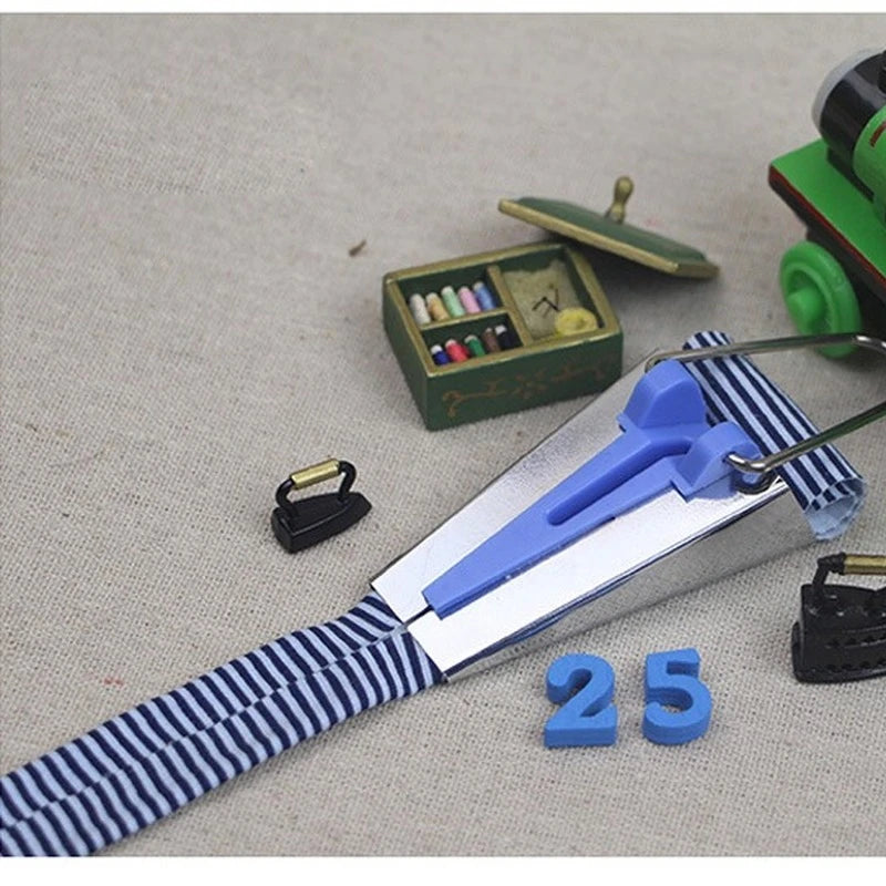 A precision bias tape maker set with blue and silver components and numbered pieces on a light fabric background.
