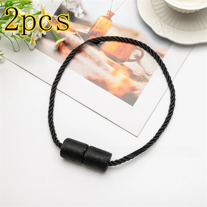 A set of two black magnetic curtain tiebacks displayed on a white surface next to a photo.