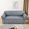 A gray stretch knit sofa cover featuring a bubble lattice texture placed on a wooden floor.