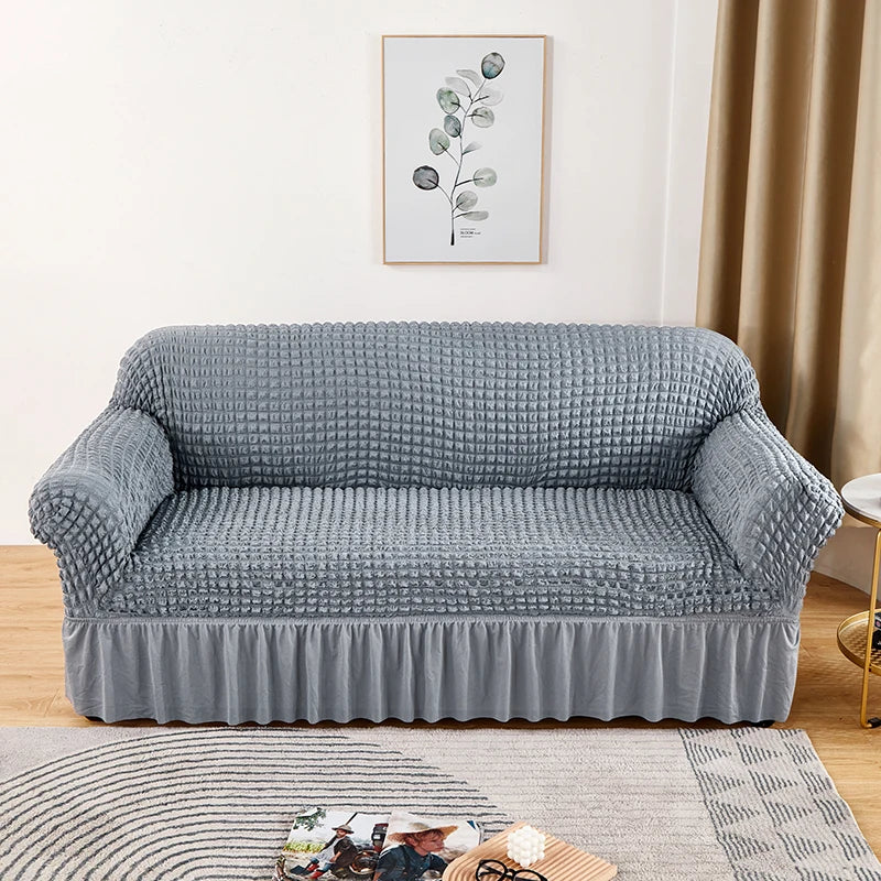 A gray stretch knit sofa cover featuring a bubble lattice texture placed on a wooden floor.