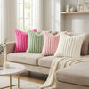 A collection of pink, green, and cream faux fur decorative throw pillows displayed on a beige sofa.