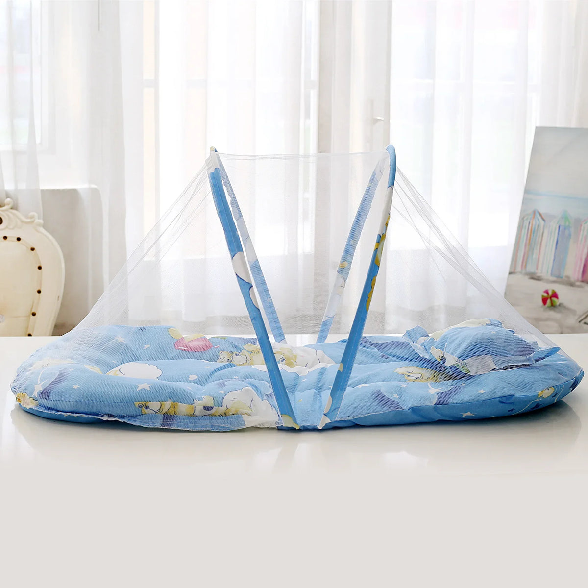 A portable baby crib net with soft blue and yellow padding is displayed on a white surface.