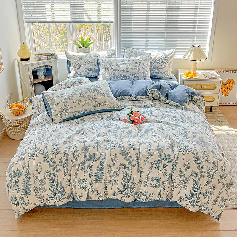 A light blue floral printed bedding set featuring various pillows and a duvet on a bed.
