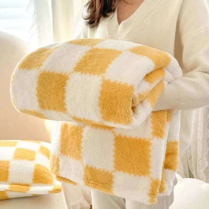 A yellow and white checkered soft flannel fleece blanket being held by a person.