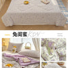 A purple and white cartoon pattern lightweight summer quilt displayed on a bed.