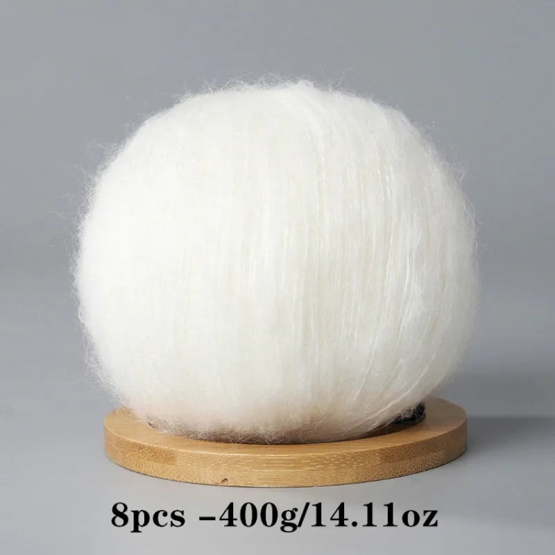 A ball of white mohair yarn used for crafting, displayed on a wooden base.