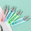 A collection of U-shape sewing scissors in various pastel colors, including pink, light blue, and lime green, laid on a white