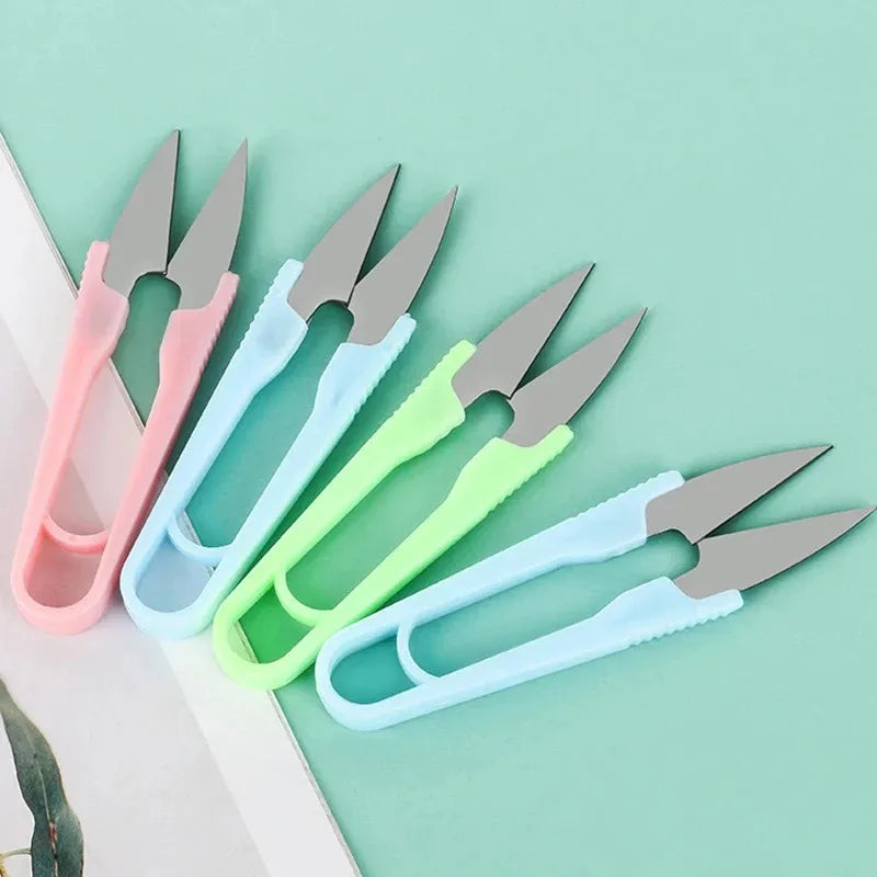 A collection of U-shape sewing scissors in various pastel colors, including pink, light blue, and lime green, laid on a white