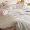 A close-up of a white duvet cover set with pink and white pillows on a bed.