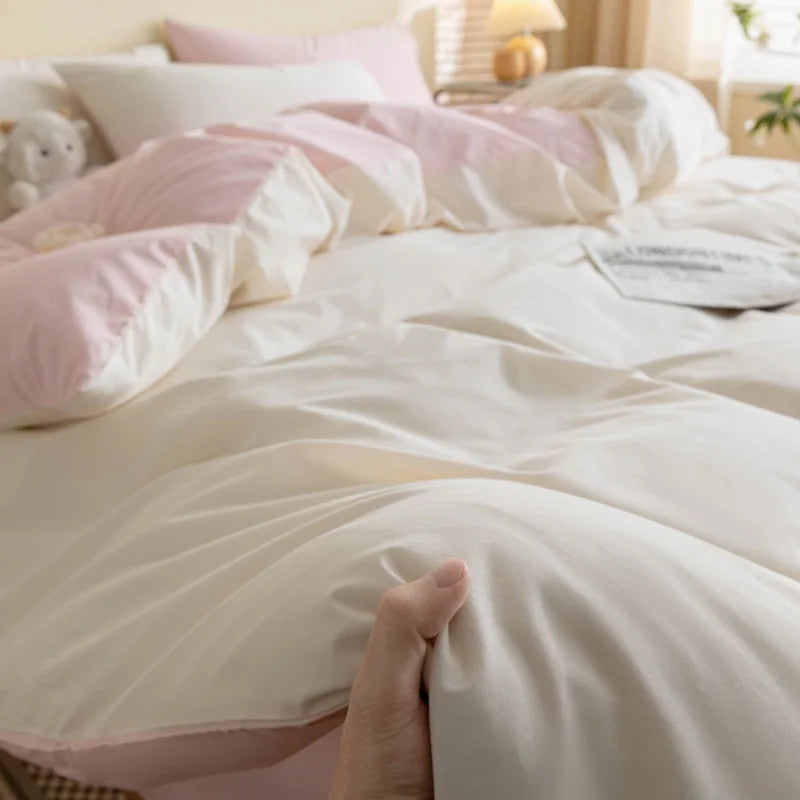 A close-up of a white duvet cover set with pink and white pillows on a bed.