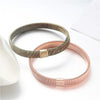 Two adjustable metal sleeve garters for men, one silver and one rose gold, displayed on a white surface.