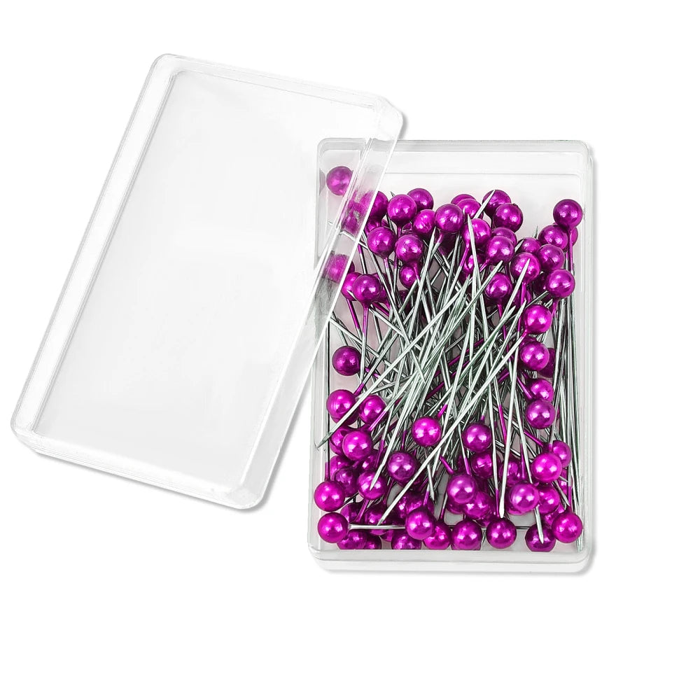 A clear plastic container holds a pack of 100 colorful purple pearl head sewing pins.
