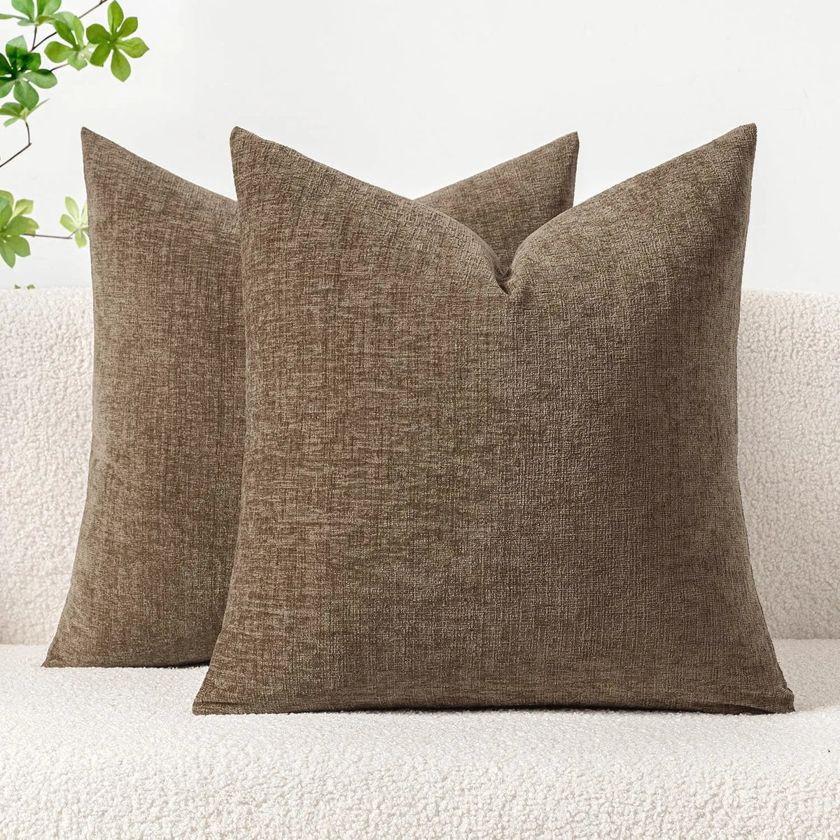 A solid olive green chenille throw pillow cover resting on a white textured sofa.