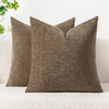 A solid olive green chenille throw pillow resting on a white textured sofa.