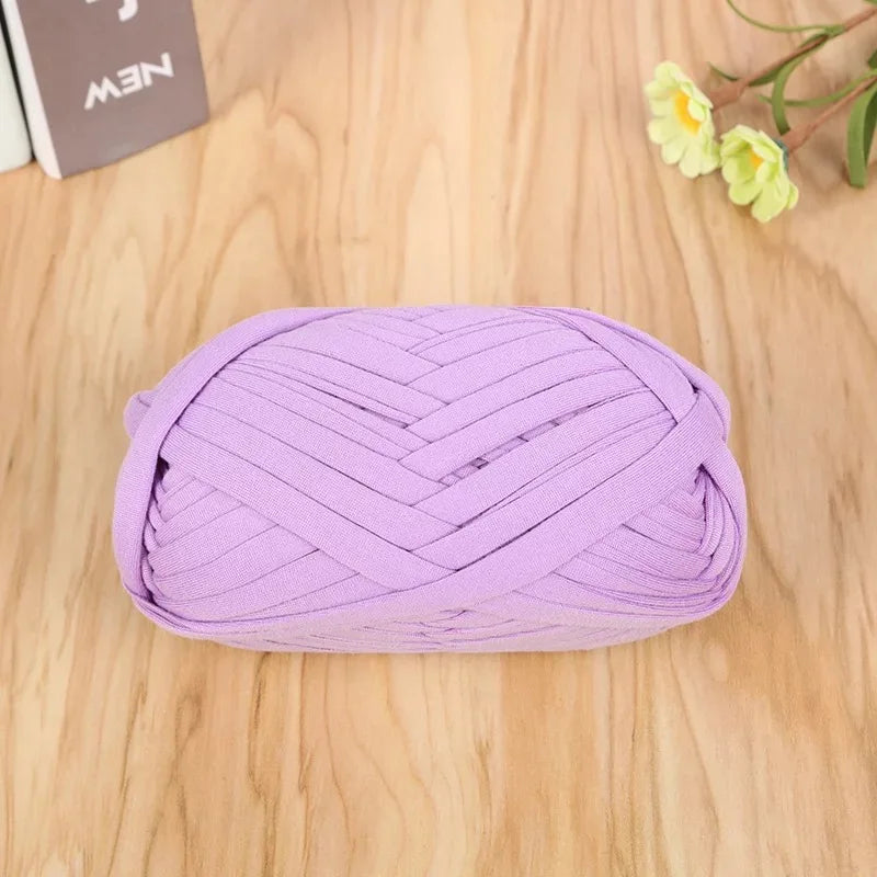 A ball of purple flat thread yarn for crafting and sewing lying on a wooden surface.