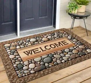 A rectangular stone doormat with the word WELCOME carved into it, placed on a wooden porch.