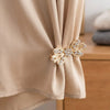 Elegant rhinestone clothing clips used to secure a beige fabric scarf.