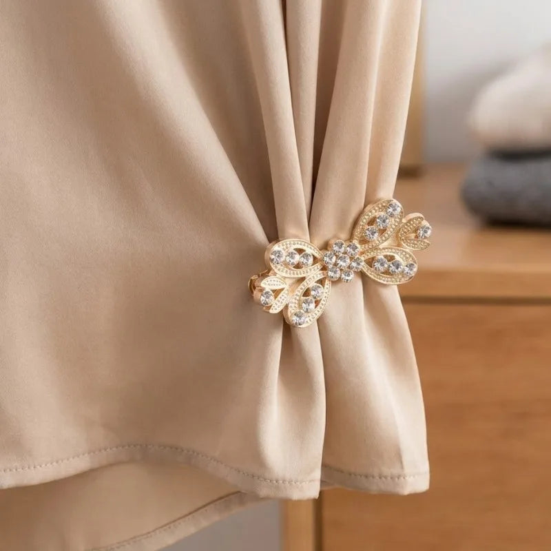 Elegant rhinestone clothing clips used to secure a beige fabric scarf.