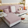 A light pink jacquard elastic sofa slipcover with white cushions and orange accents in a modern living room setting.