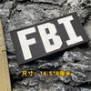 A black tactical hook and loop patch with white FBI lettering is displayed on a rough gray rock surface.