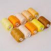 A collection of ten rolls of high-quality polyester sewing thread in various colors including yellow, orange, beige, and gold