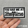Black and white embroidered patch with the text YOU HAD ME AT Halftime on a gray fabric background