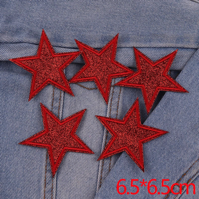 Five red glitter star patches are placed on a denim fabric background.