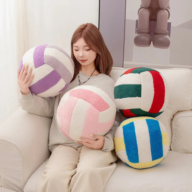 A woman is holding several colorful plush volleyball balls on a white sofa.