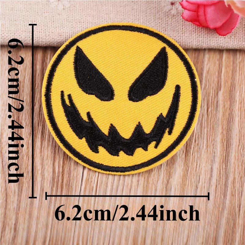 A round yellow embroidered patch featuring a black menacing monster face on a wooden surface.