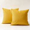 Two mustard yellow velvet cushion covers lying on a white surface.