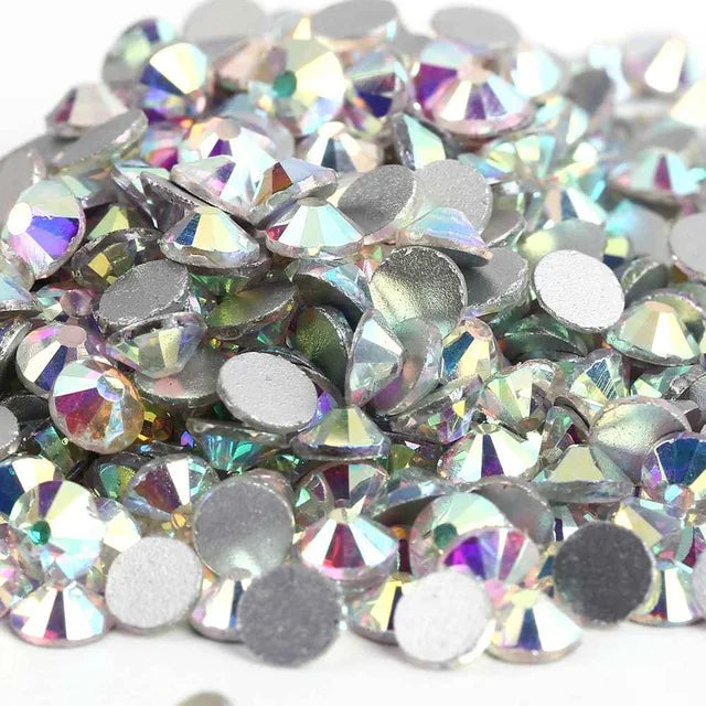A pile of iridescent crystal AB flatback rhinestones in various shades of silver and purple.