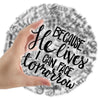 A hand holds a transparent sticker featuring the Bible verse He lives I can face tomorrow on a background of script.