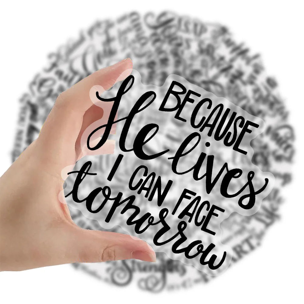 A hand holds a transparent sticker featuring the Bible verse He lives I can face tomorrow on a background of script.